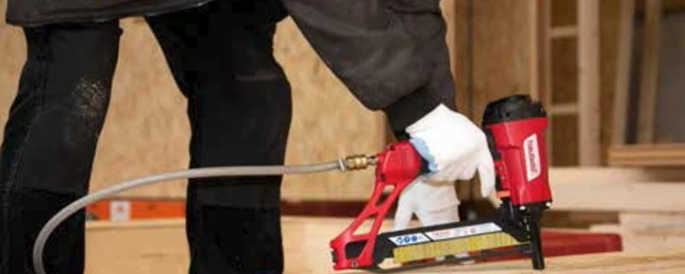 Handwerker nagelt mit einem Druckluftnagler an einer Holzkiste
